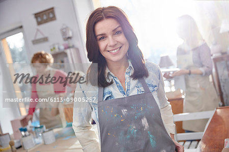 Portrait smiling, confident female artist painting in art class workshop