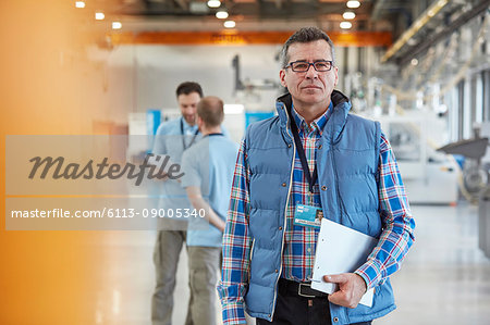 Portrait confident male supervisor with clipboard in factory