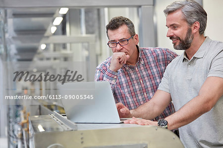 Male supervisors using laptop in factory