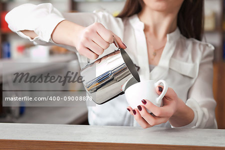white cup of coffee with milk in woman's hand