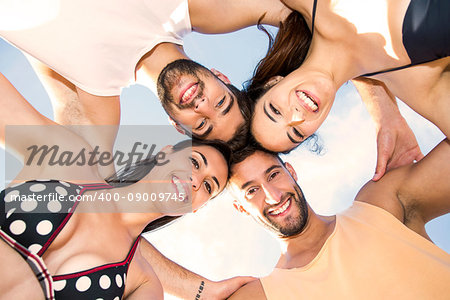 Multicultural group of friends embraced together at the beach