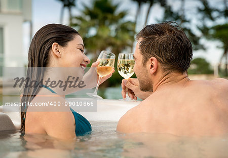 Young couple inside a jacuzzi and toasting