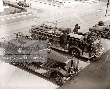 1950s 1960s TOP VIEW OF TWO FIRE TRUCKS PARKED AT STATION FIREMEN ON TRUCK WEARING PROTECTIVE EQUIPMENT
