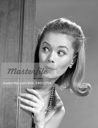 1960s WOMAN PEEKING AROUND DOOR WITH FUNNY FACIAL EXPRESSION