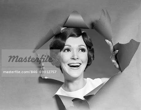 1960s 1960s WOMAN SMILING LOOKING BREAKING THROUGH TORN PAPER