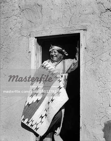 1930s SMILING NATIVE AMERICAN INDIAN MAN STANDING IN DOORWAY WEARING TYPICAL COSTUME SAN ILDEFONSO PUEBLO NEW MEXICO USA