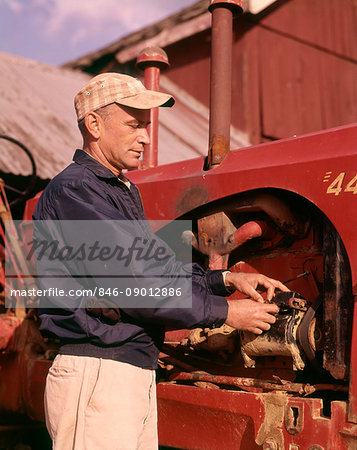 1960s MAN FARMER REPAIRING TRACTOR FARM EQUIPMENT MACHINERY