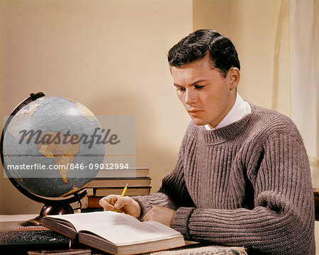 1950s 1960s TEENAGE BOY STUDENT STUDYING AT DESK WITH GLOBE OPEN TEXTBOOKS COLLEGE AGE