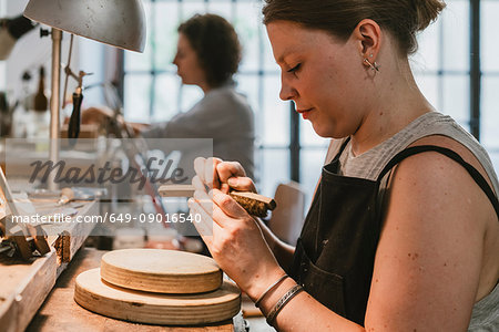 Female jeweller using wire brush workbench