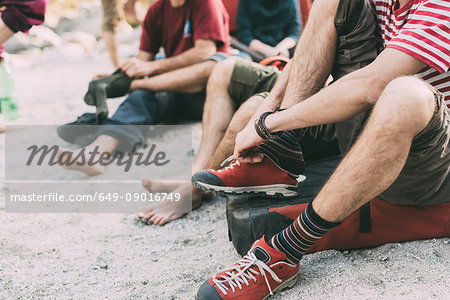 Neck down view of adult bouldering friends putting on socks and trainers, Lombardy, Italy