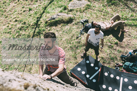 High angle view of young male boulderer climbing boulder, Lombardy, Italy