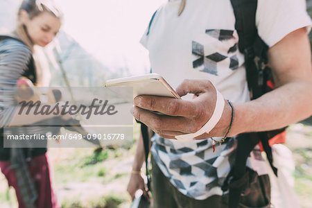 Hand of male boulderer holding smartphone, Lombardy, Italy