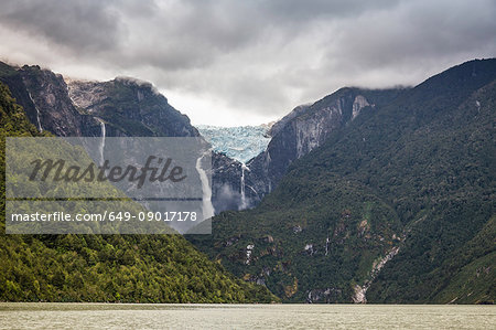 Waterfall flowing from glazier at edge of mountain rock face, Queulat National Park, Chile