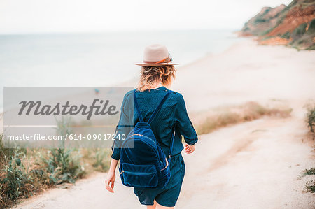 Mid adult woman walking towards beach, rear view