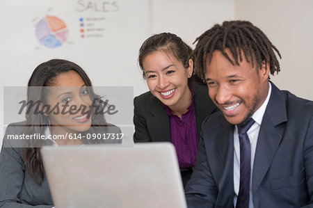 Businessman and businesswomen, in office, looking at laptop