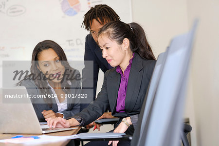 Businessman and businesswomen in office, looking at laptop screen