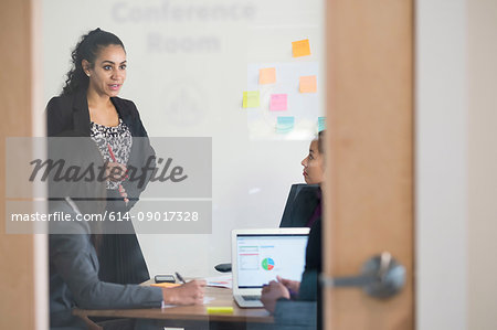 Businessman and businesswomen, in office meeting, using laptop, looking at data