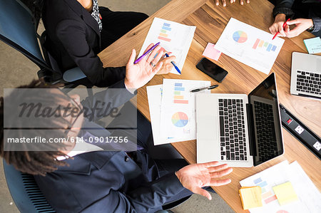 Businessman and businesswomen, in office meeting, using laptops, looking at data, overhead view