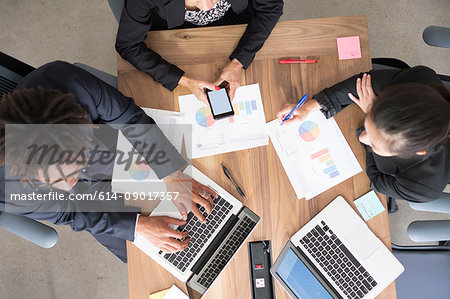 Businessman and businesswomen, in office meeting, using laptops, looking at data, overhead view
