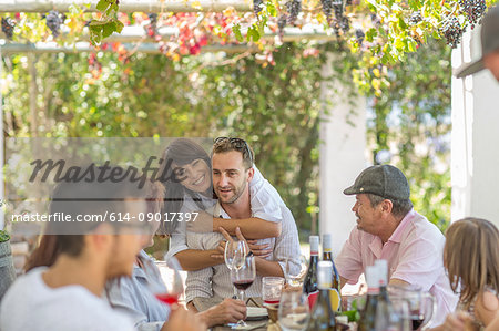 Family having lunch outdoor under grapevine trellis