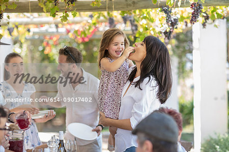 Girl feeding mother at outdoor family lunch