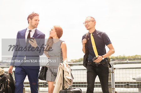 Businessmen and woman walking with luggage on waterfront, New York, USA