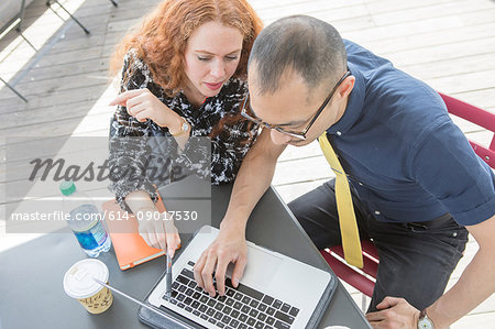 Businessman and woman using laptop at cafe table