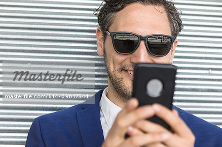 Young businessman in sunglasses looking at smartphone