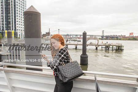 Young businesswoman on ferry deck looking at smartphone, New York, USA