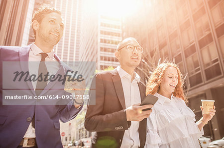 Businessmen and woman strolling along city sidewalk, New York, USA