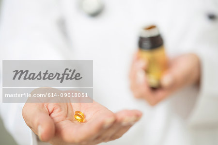 Cropped view of doctor holding pill bottle and pills