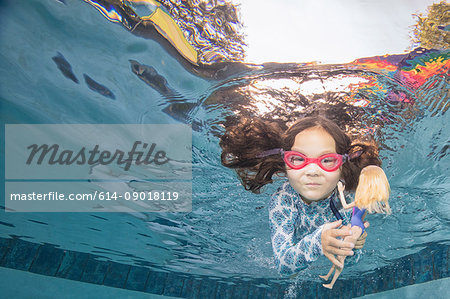 Underwater portrait of girl swimming holding doll