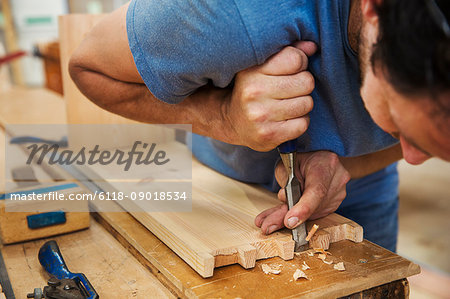 Close up of man working a boat-builder's workshop, joining together two pieces of wood.