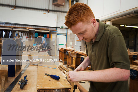 Man working a boat-builder's workshop, joining together two pieces of wood.