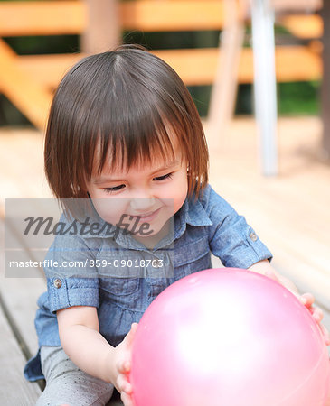 Mixed-race young girl playing with ball on wooden deck