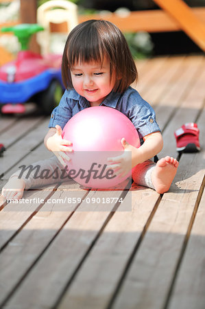 Mixed-race young girl playing with ball on wooden deck