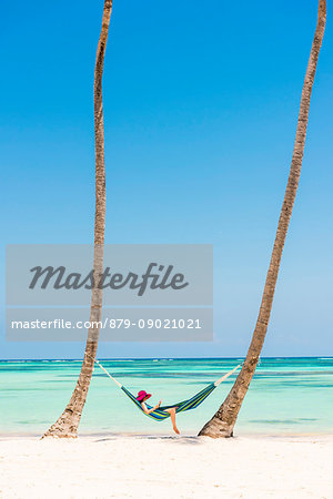 Juanillo Beach (playa Juanillo), Punta Cana, Dominican Republic. Woman relaxing on a hammock on a palm-fringed beach (MR).
