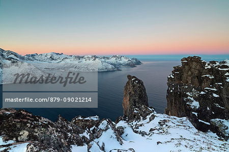 View of the Mefjorden framed by frozen sea and pink sky at sunrise from the top of Mount Hesten Senja Tromsø Norway Europe