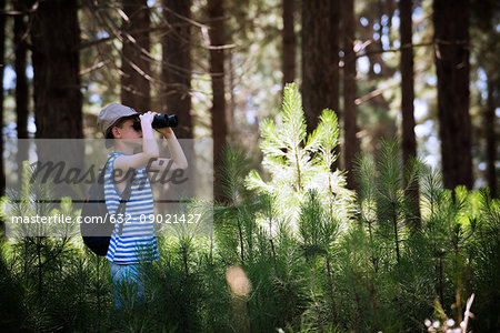 Boy looking through binoculars in woods