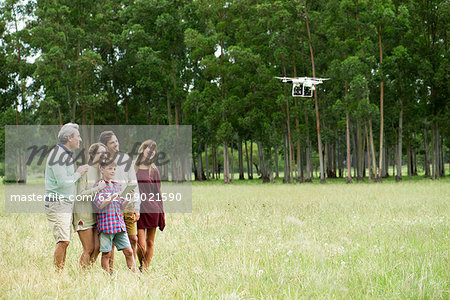 Boy operating remote control drone while parents and grandparents watch