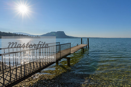 Sun shining on Lake Garda (Lago di Gardo) with wooden jetty in the summer at Garda in Veneto, Italy