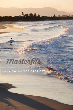 Silhouette of surfer watching waves hitting shore on beach at Byron Bay in New South Wales, Australia