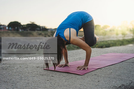 Mature woman outdoors, balancing on hands in yoga position
