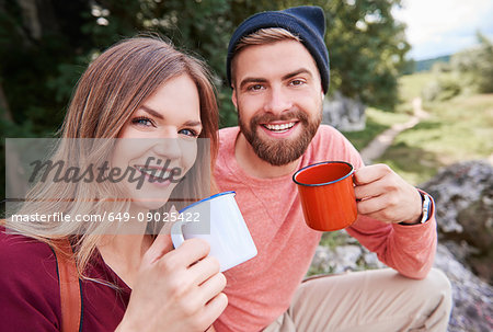 Portrait of couple holding enamel mugs looking at camera smiling, Krakow, Malopolskie, Poland, Europe