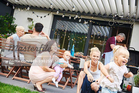 Female toddler playing at three generation family lunch on patio