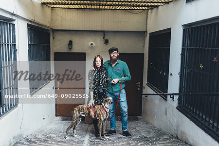 Portrait of cool couple with dog outside apartment