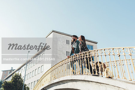 Low angle view of couple with dog looking out from footbridge