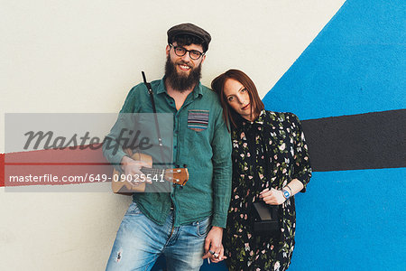 Portrait of cool couple leaning against abstract wall