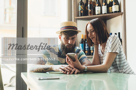 Couple looking at smartphone at bar table