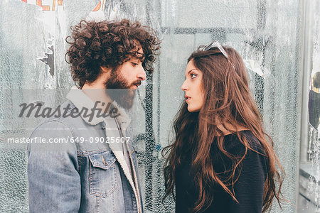 Young man and woman, standing face to face, pensive expressions